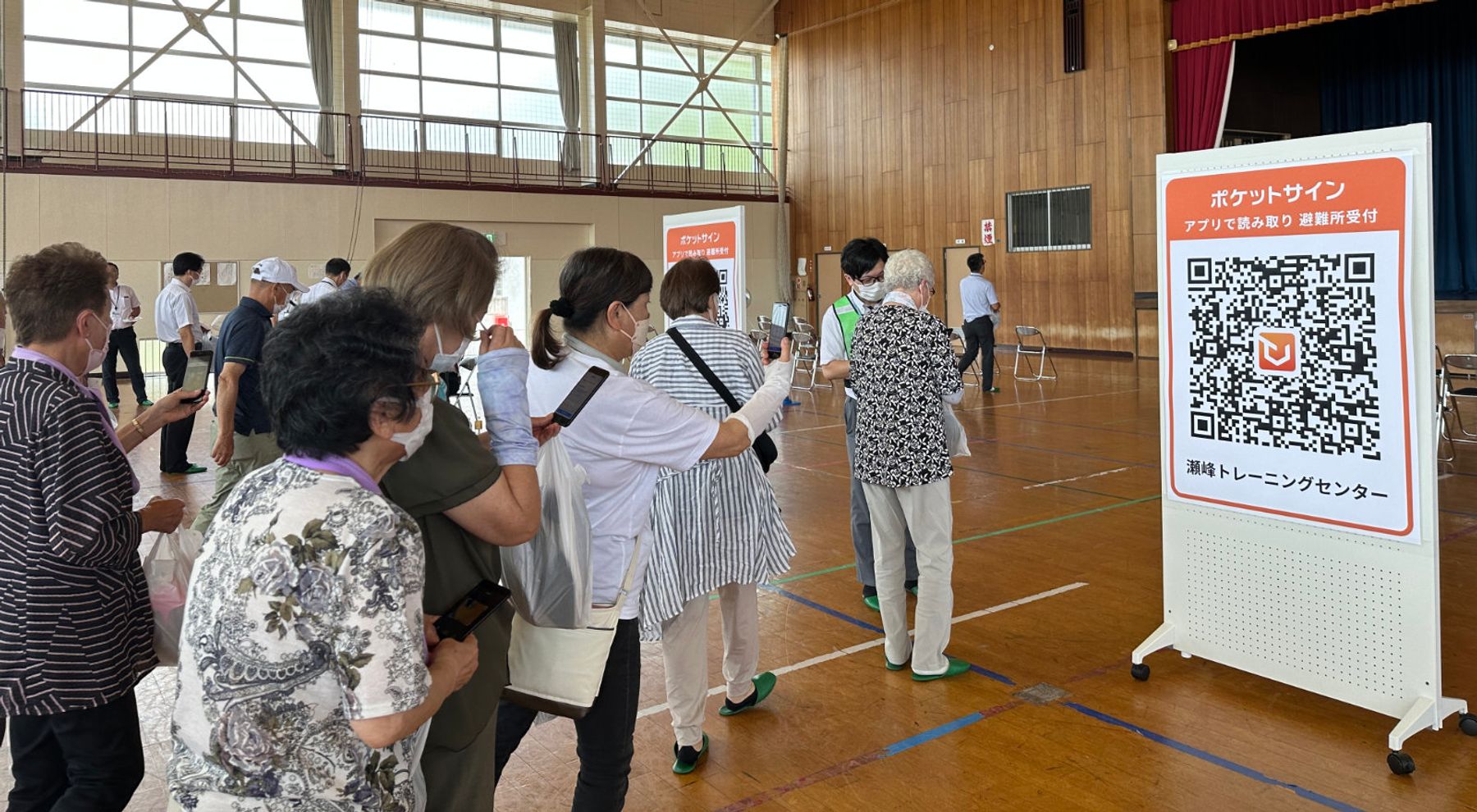 避難所でアプリを使ってチェックインする女川町住民の方々